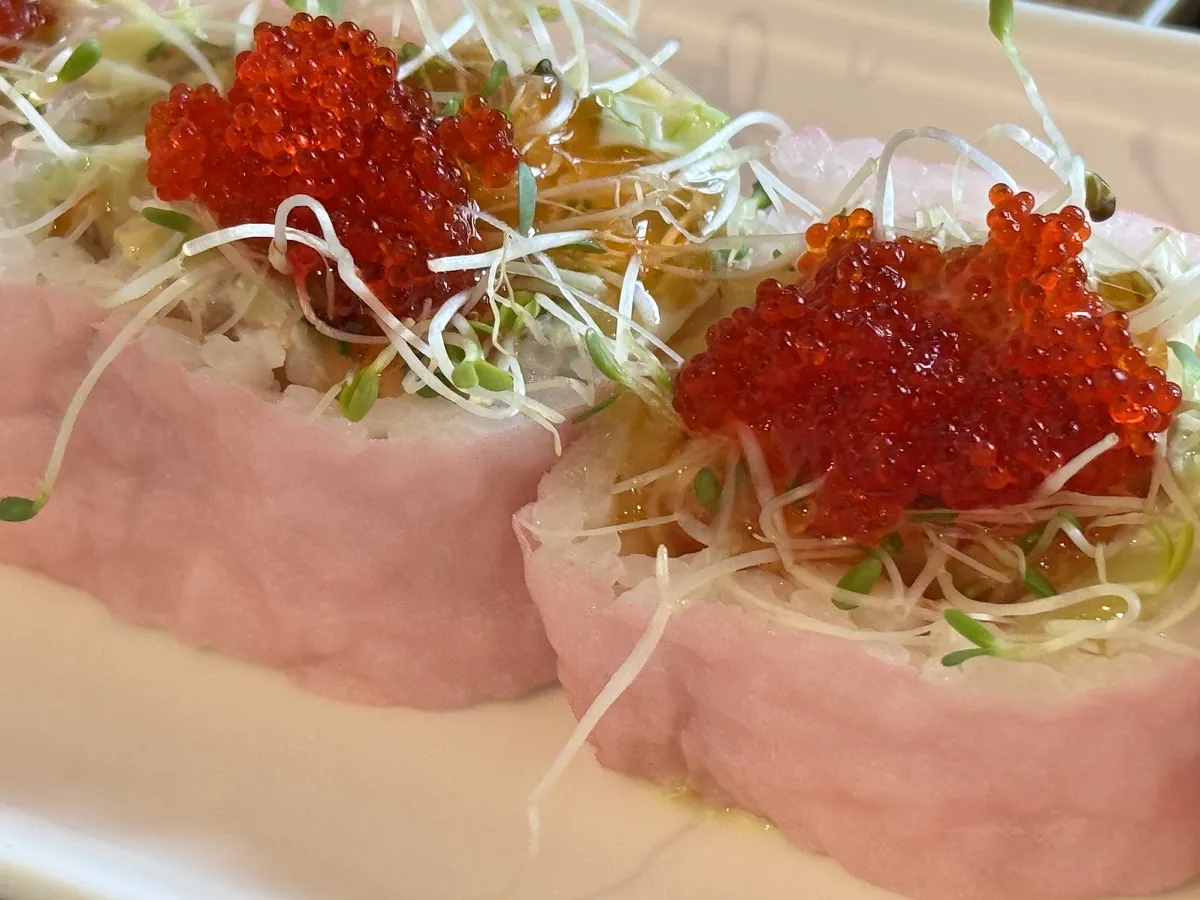 Sushi rolls with pink wrapper, red caviar, and sprouts