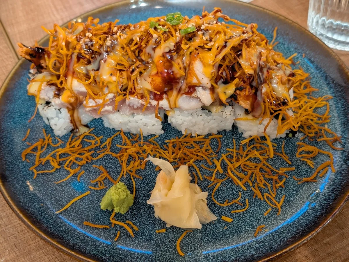 Sushi roll with crispy toppings, wasabi, and ginger